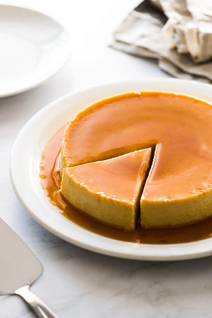 A flan presented on a serving dish with a single piece cut out but not yet removed.