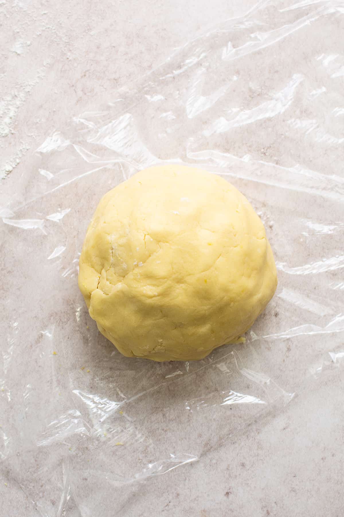 The dough for alfajores on top of a sheet of plastic wrap.