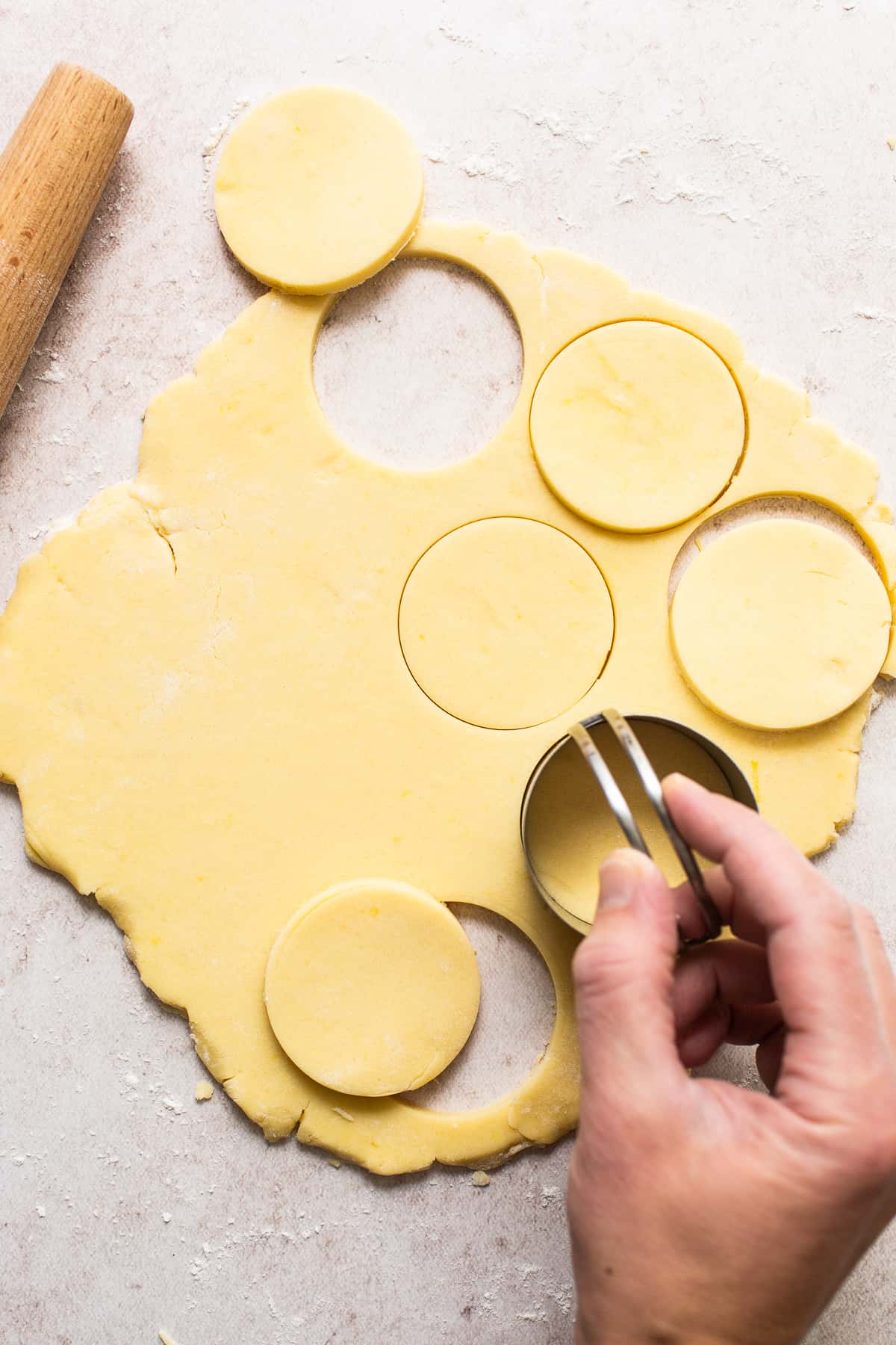 A hand stamping out alfajores cookies on a table.