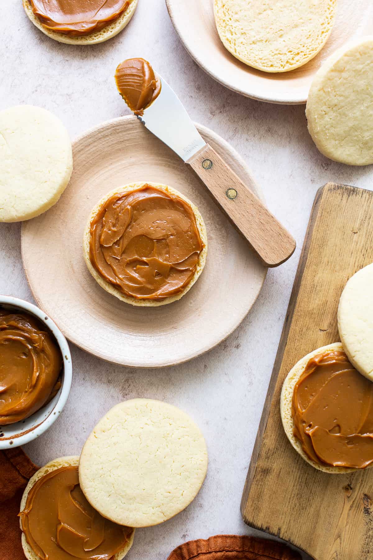 Dulce de leche being spread on alfajore cookies before being sandwiched together.