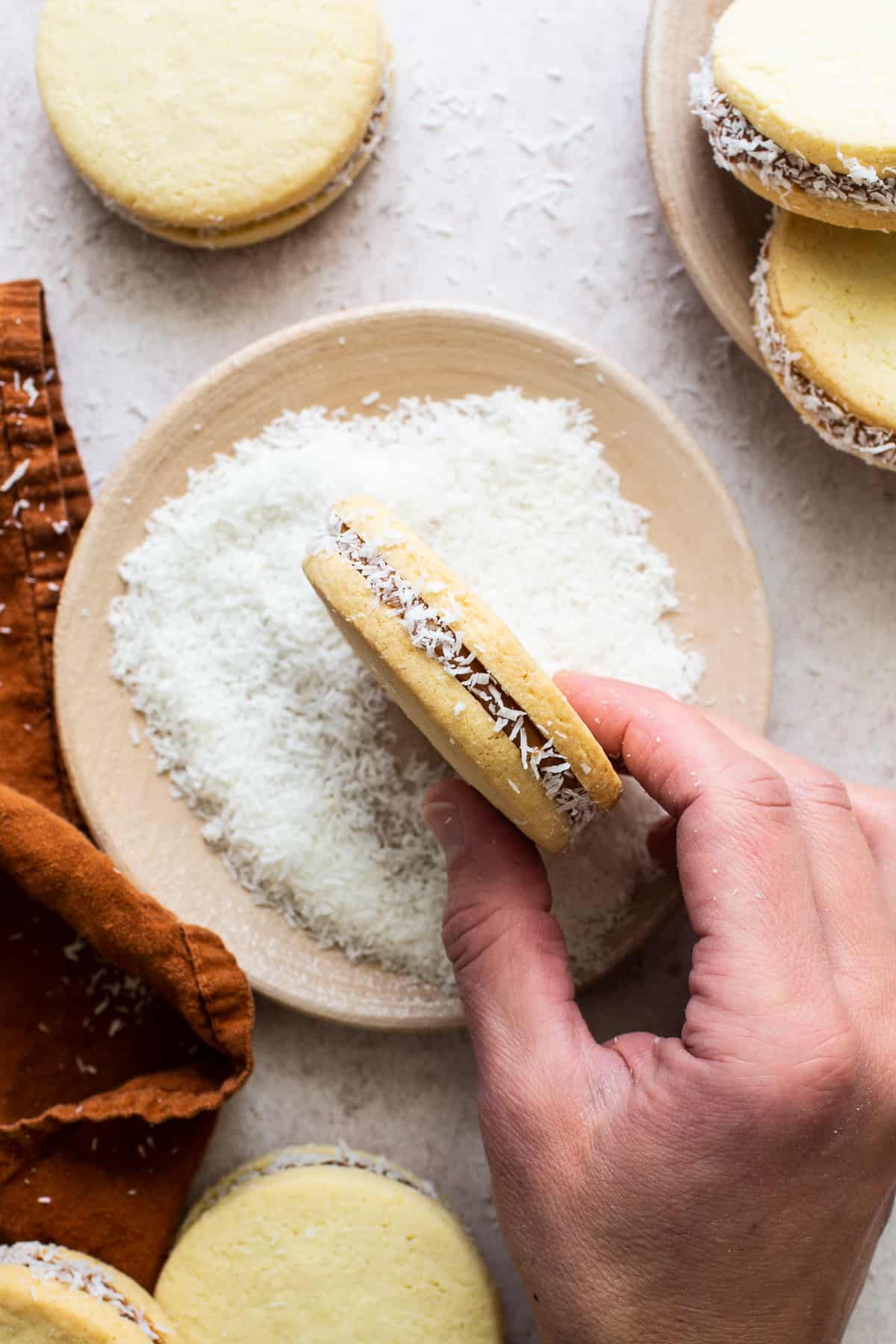 Rolling the sides of alfajores in shredded coconut.