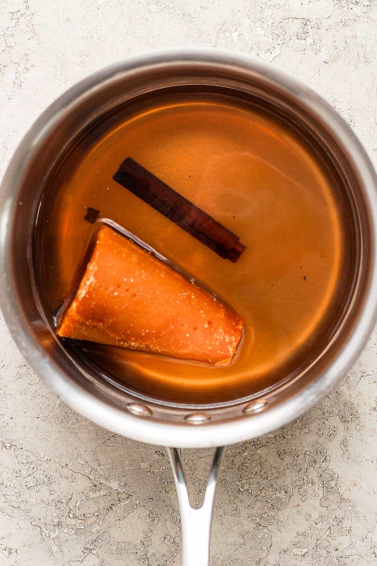 Water, piloncillo, and a cinnamon stick in a pot.