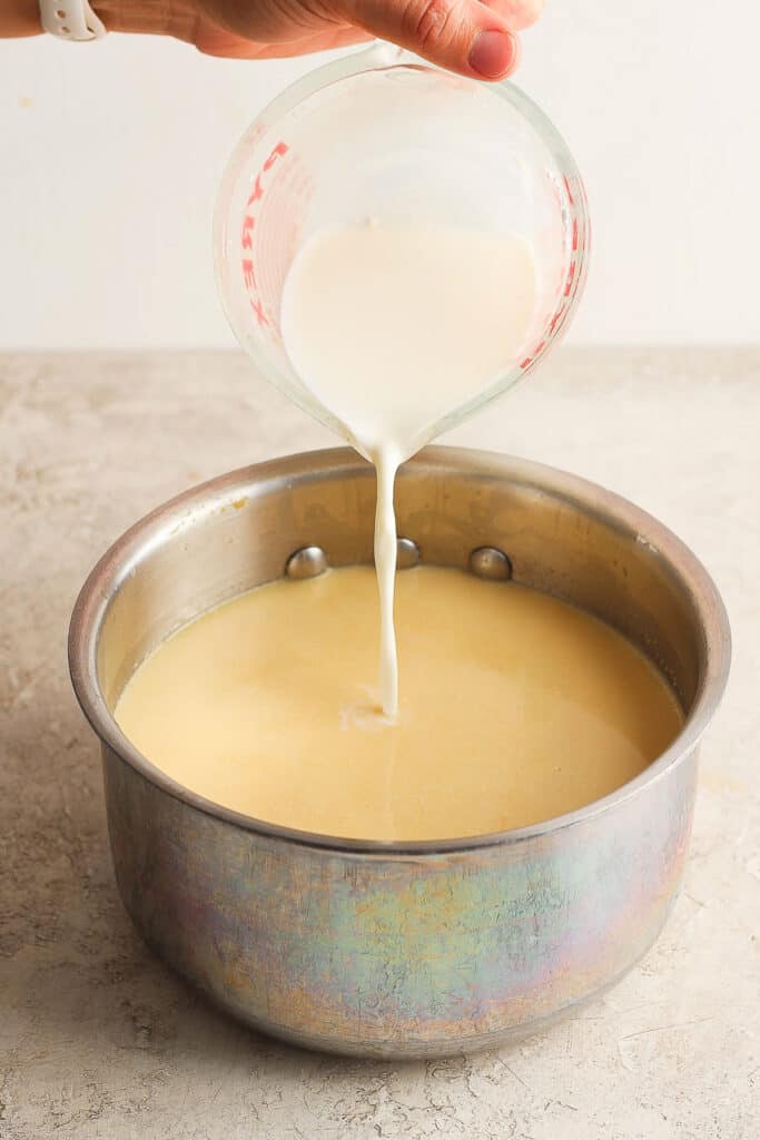 Milk being poured into a pot of atole de elote.