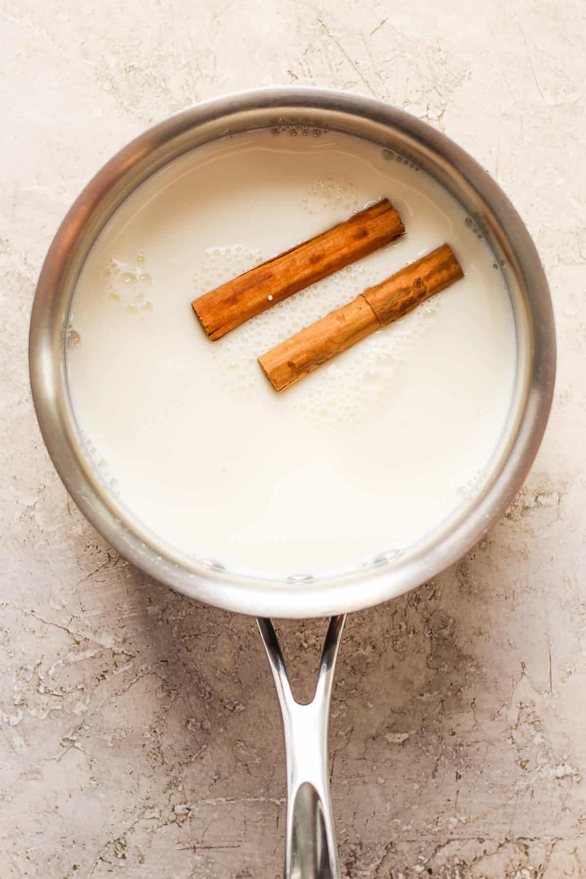 Milk and cinnamon sticks in a small pot.