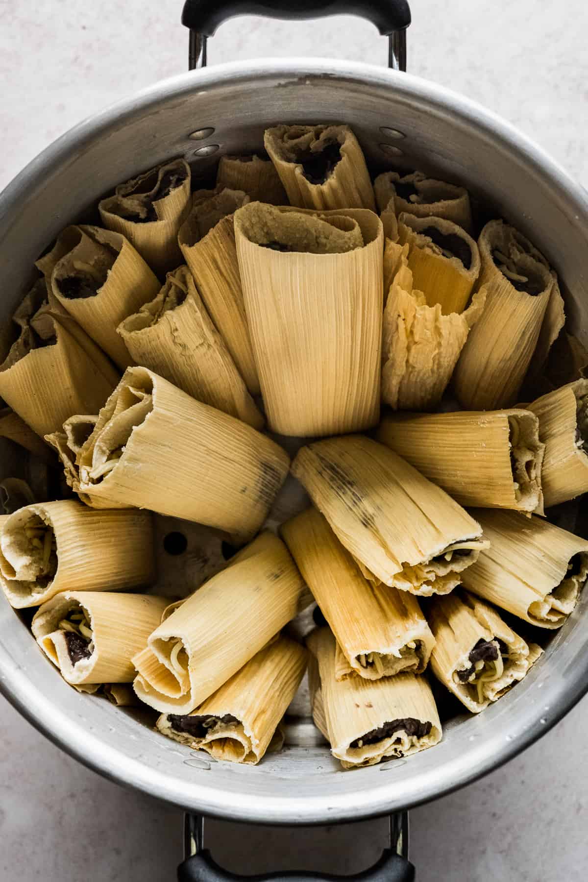 A large tamale steamer pot filled with bean and cheese tamales.