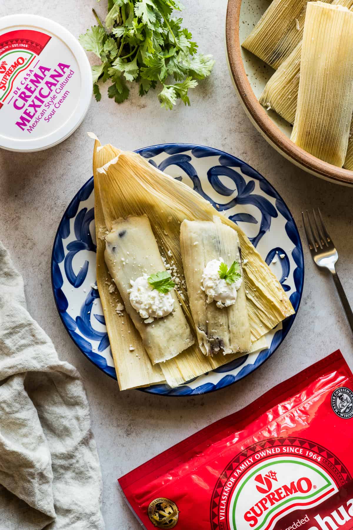 Black bean and cheese tamales garnished with crema and cotija cheese.