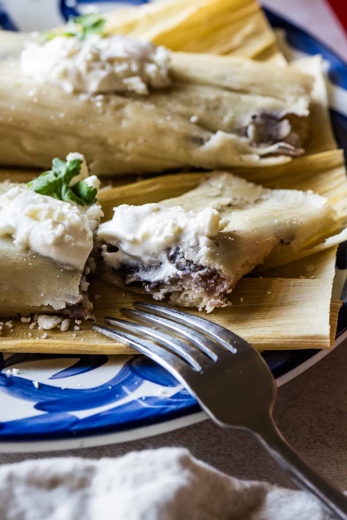 Bean and cheese tamales on a plate cut in half.