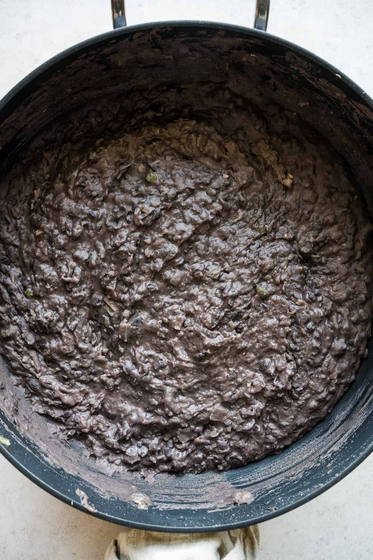 Refried black beans in a skillet.