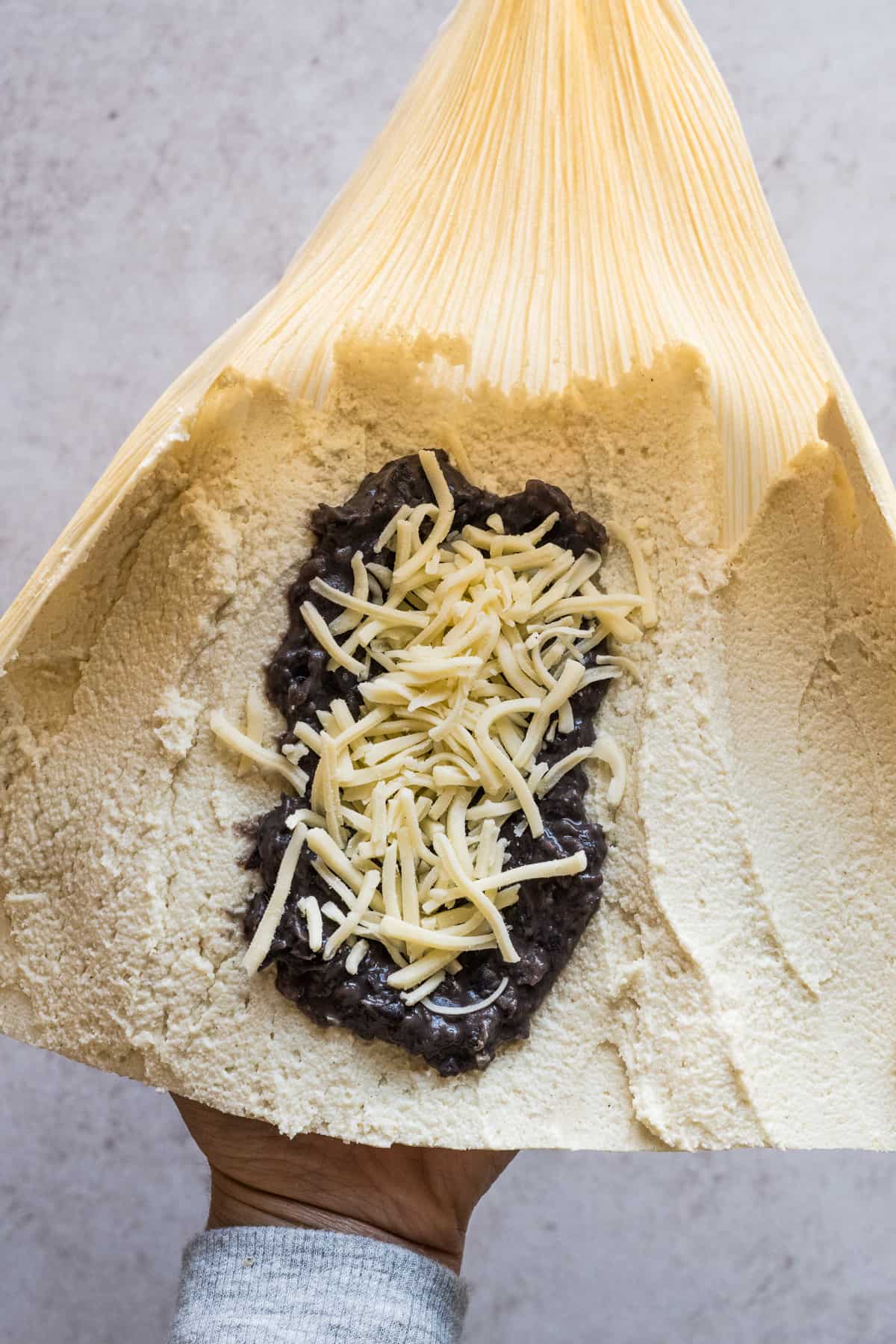 A corn husk filled with masa, refried beans, and shredded cheese.