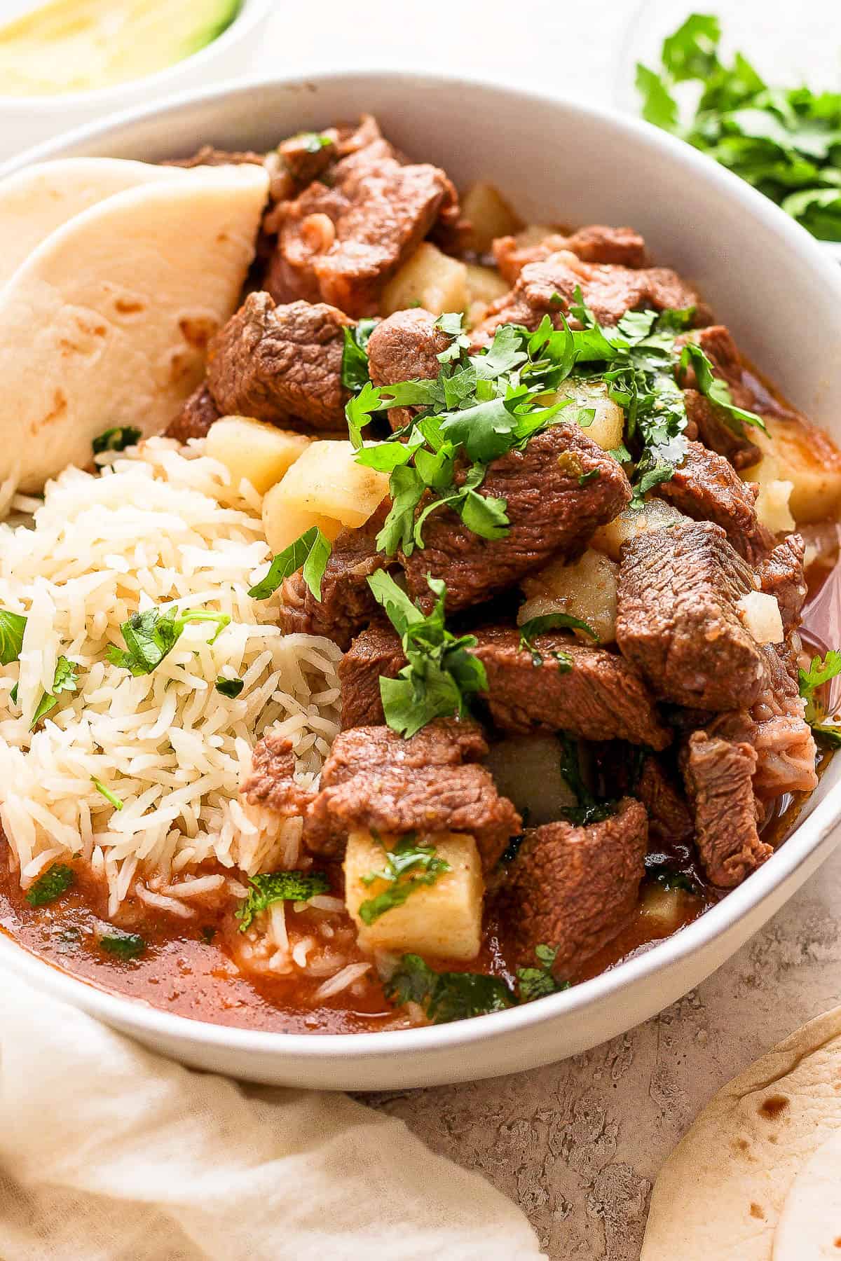 Carne con papas garnished with fresh cilantro.