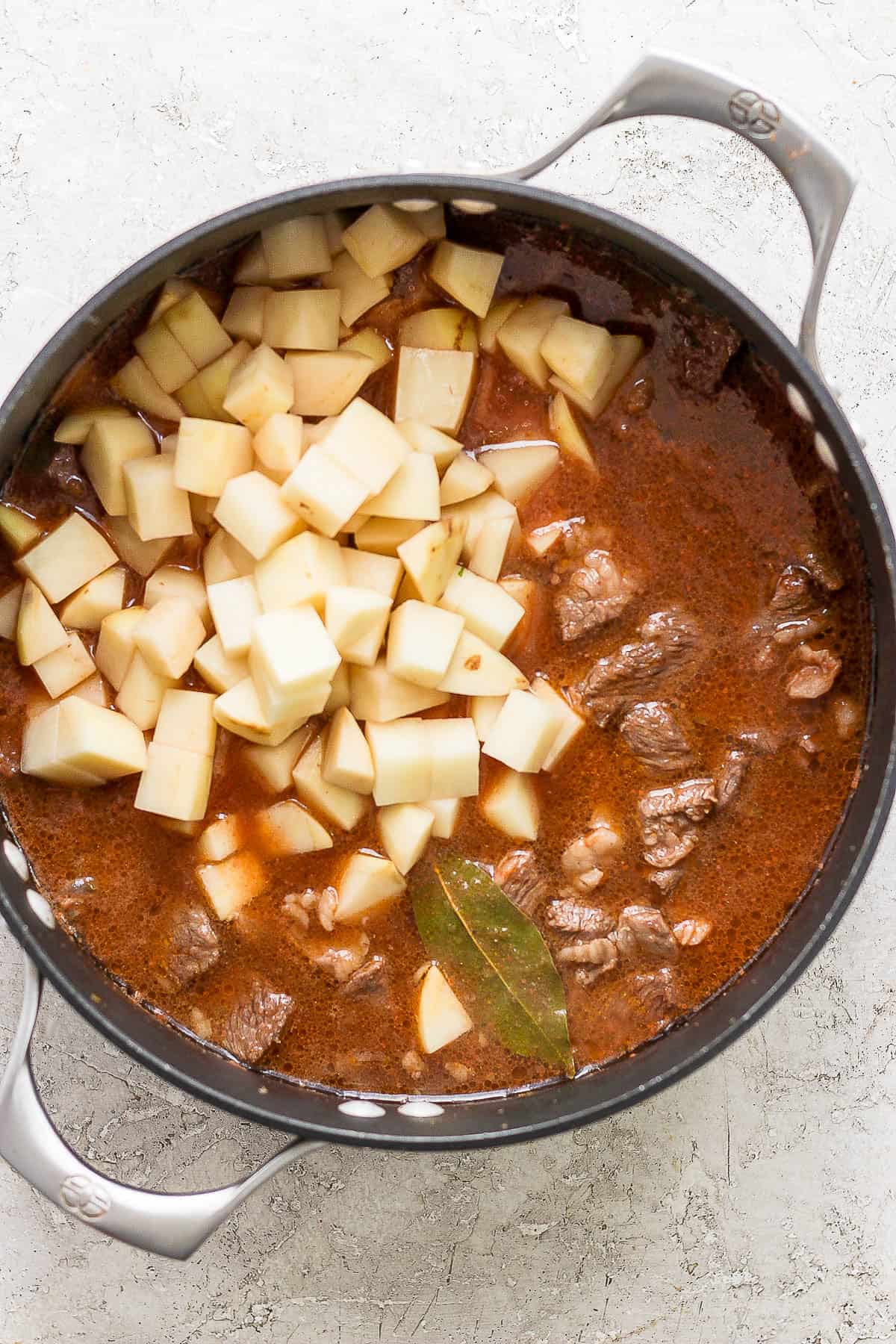 Carne con papas cooking in a pot with diced potatoes.