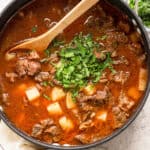 Carne con papas in a pot with cilantro stirred in.