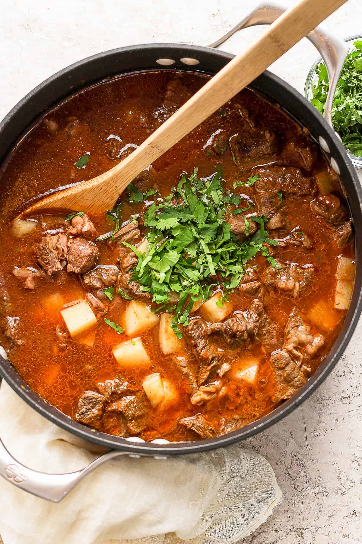 Carne con papas in a pot with cilantro stirred in.