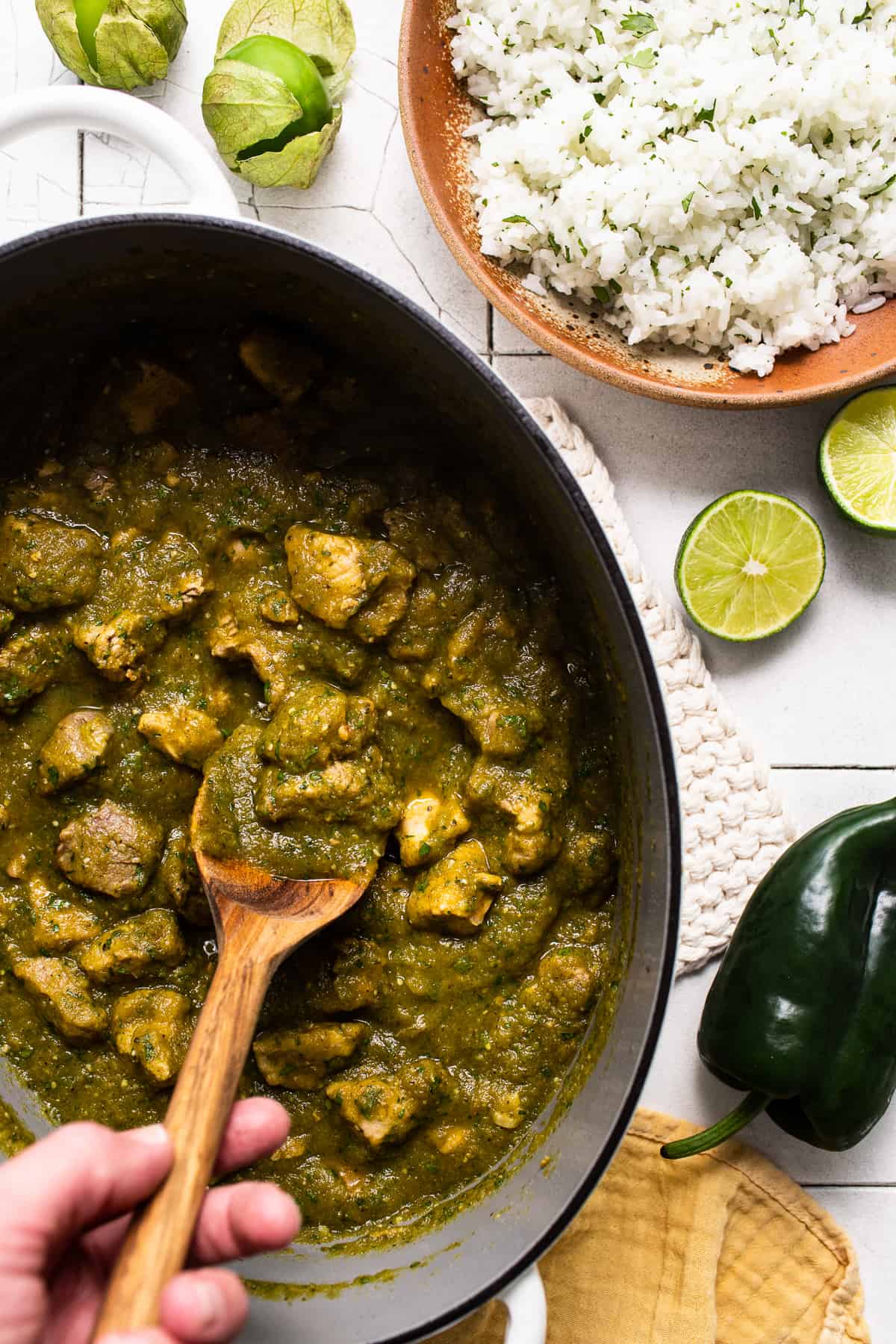 Chile verde in a pot next to a bowl of rice ready to be served together.