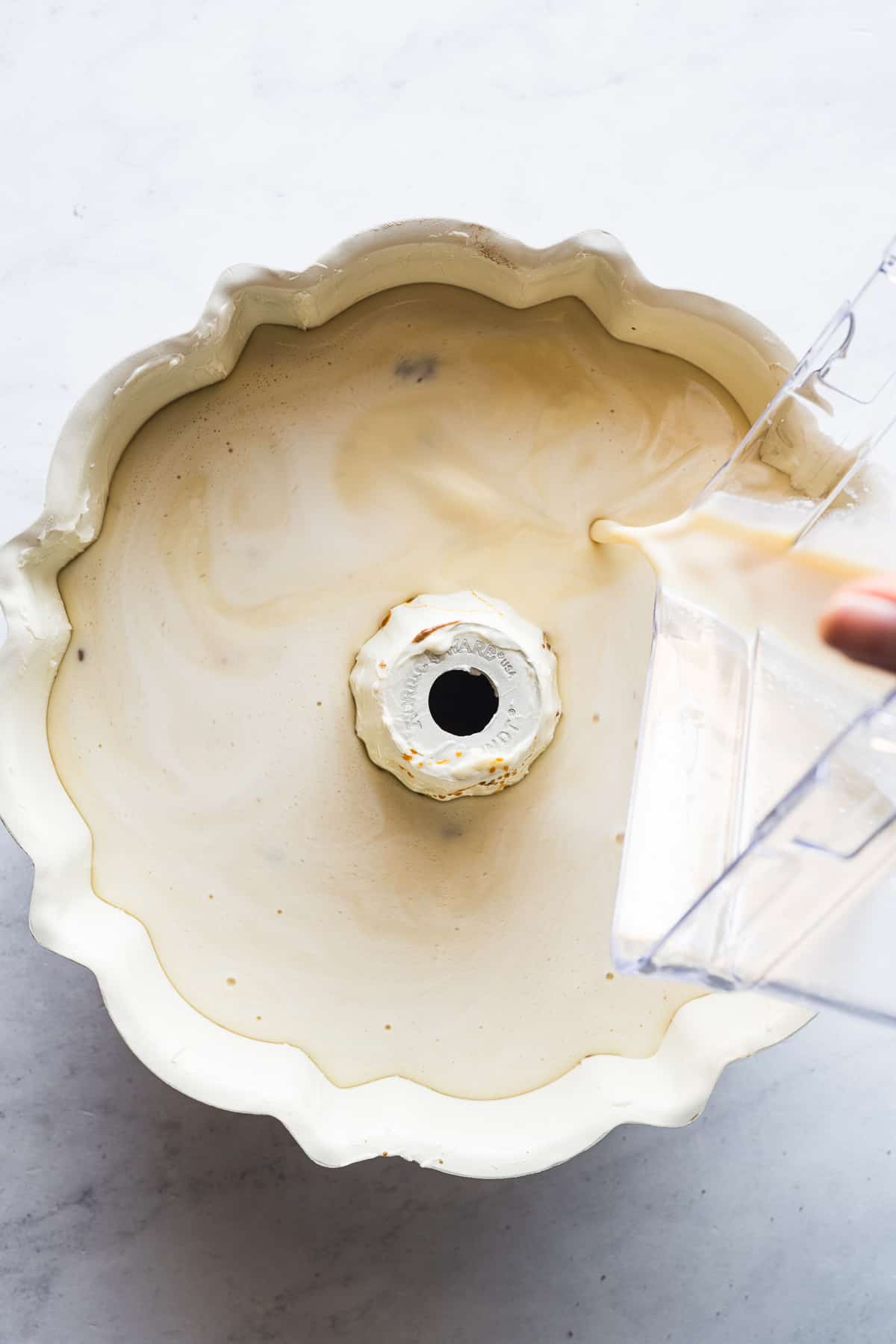 Cream cheese flan batter being poured into a bundt pan.