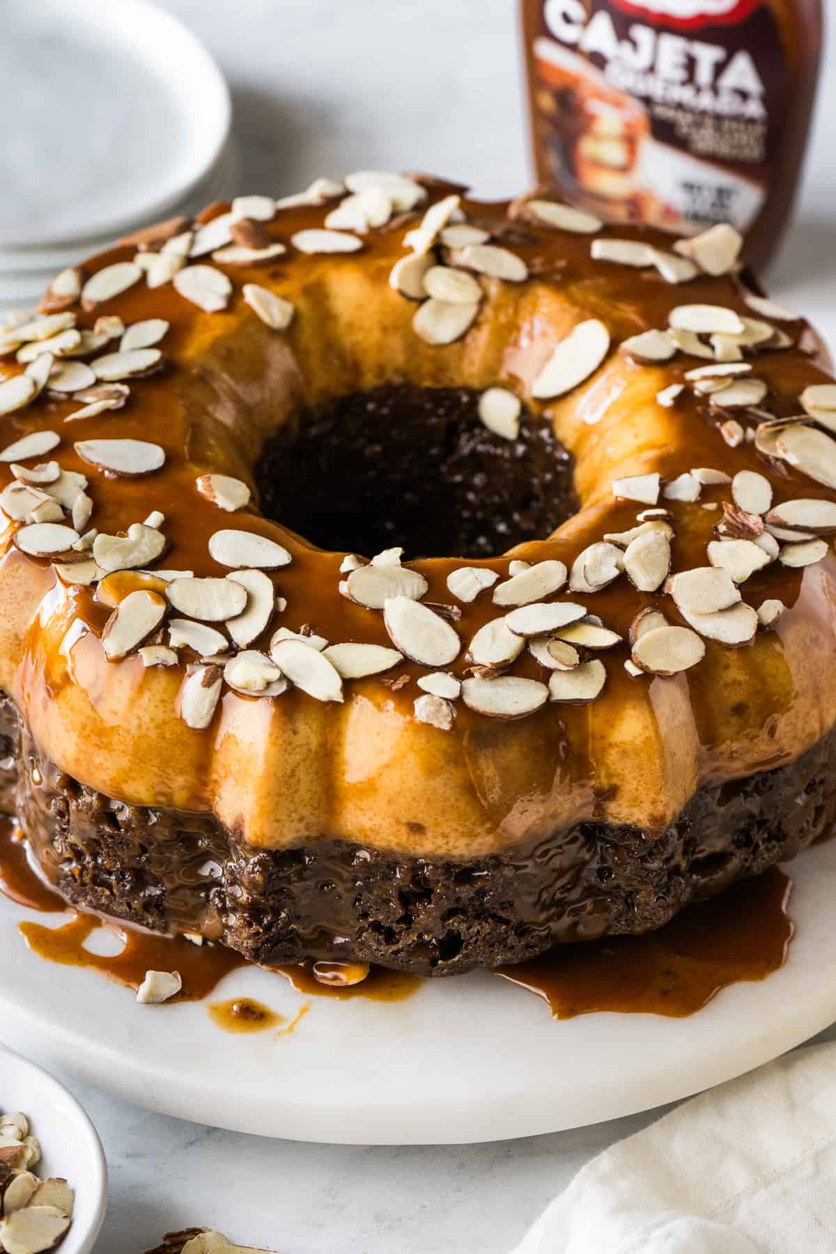 Chocoflan topped with sliced almonds and cajeta sauce.