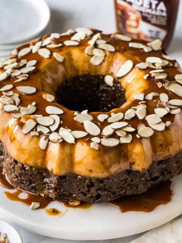 Chocoflan topped with sliced almonds and cajeta sauce.