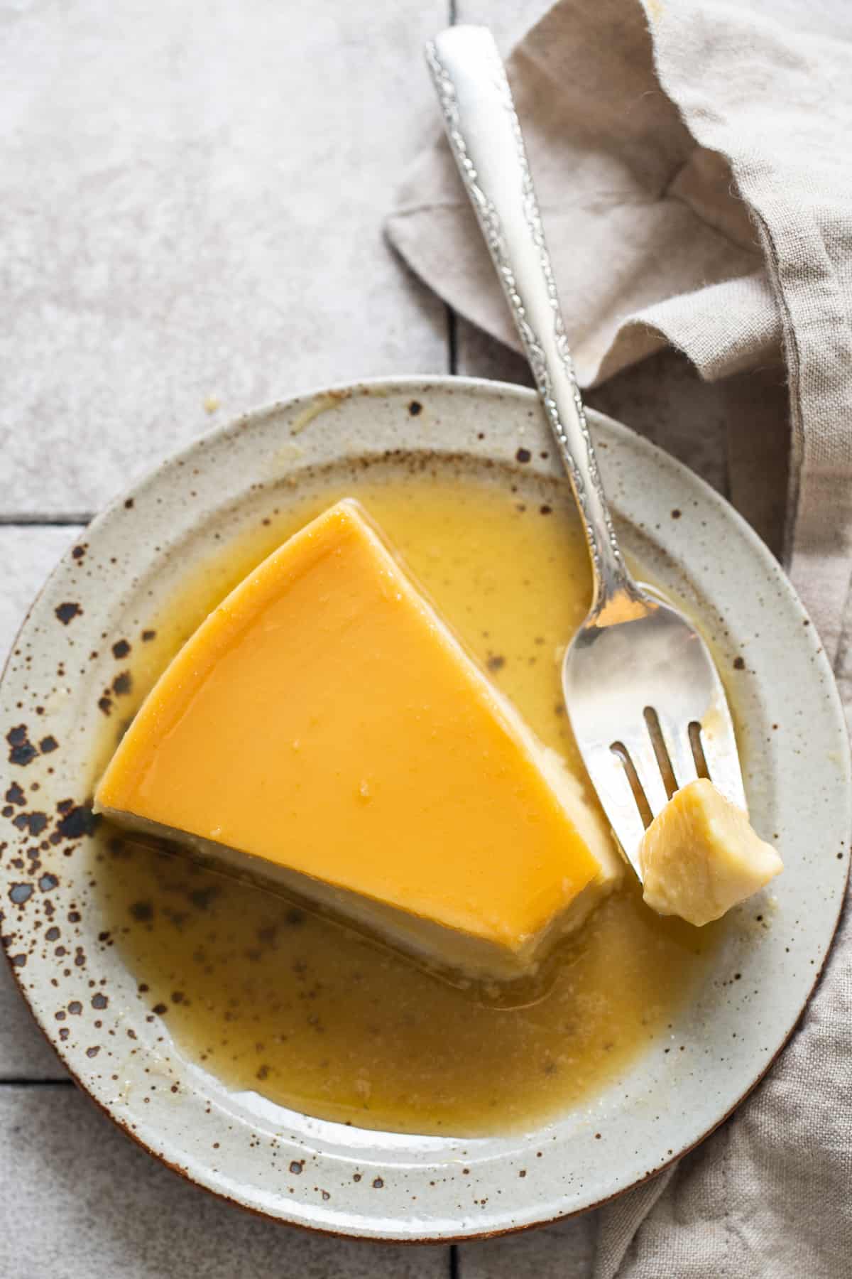 A piece of flan de queso on a fork and plate.