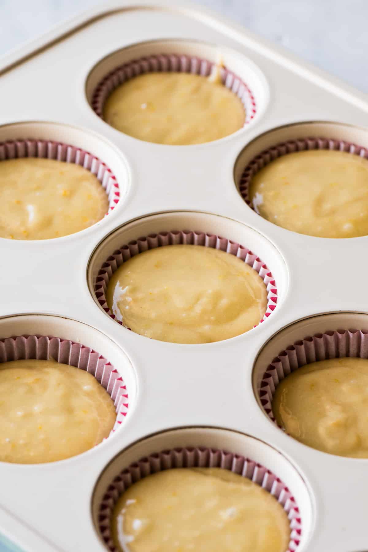 Mantecada batter filled in a muffin tin with red cupcake liners.