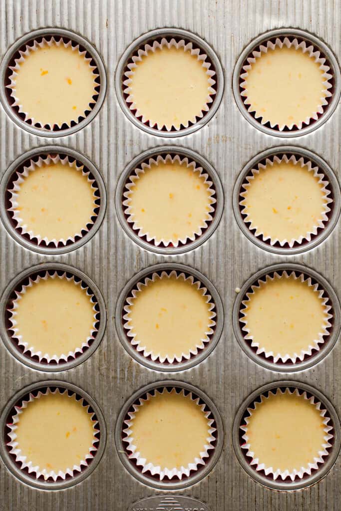 Mantecada muffin batter in a pan lined with red cupcake liners, ready to bake.
