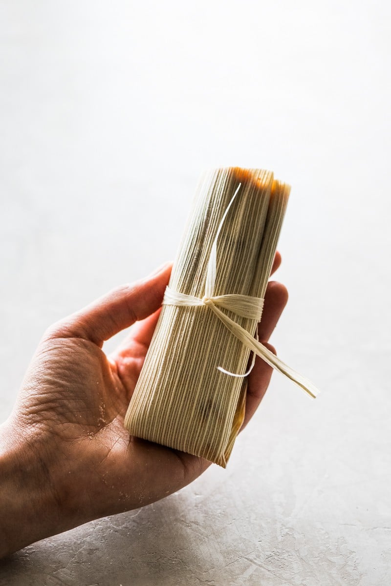 A tamal being held in someone's hand.