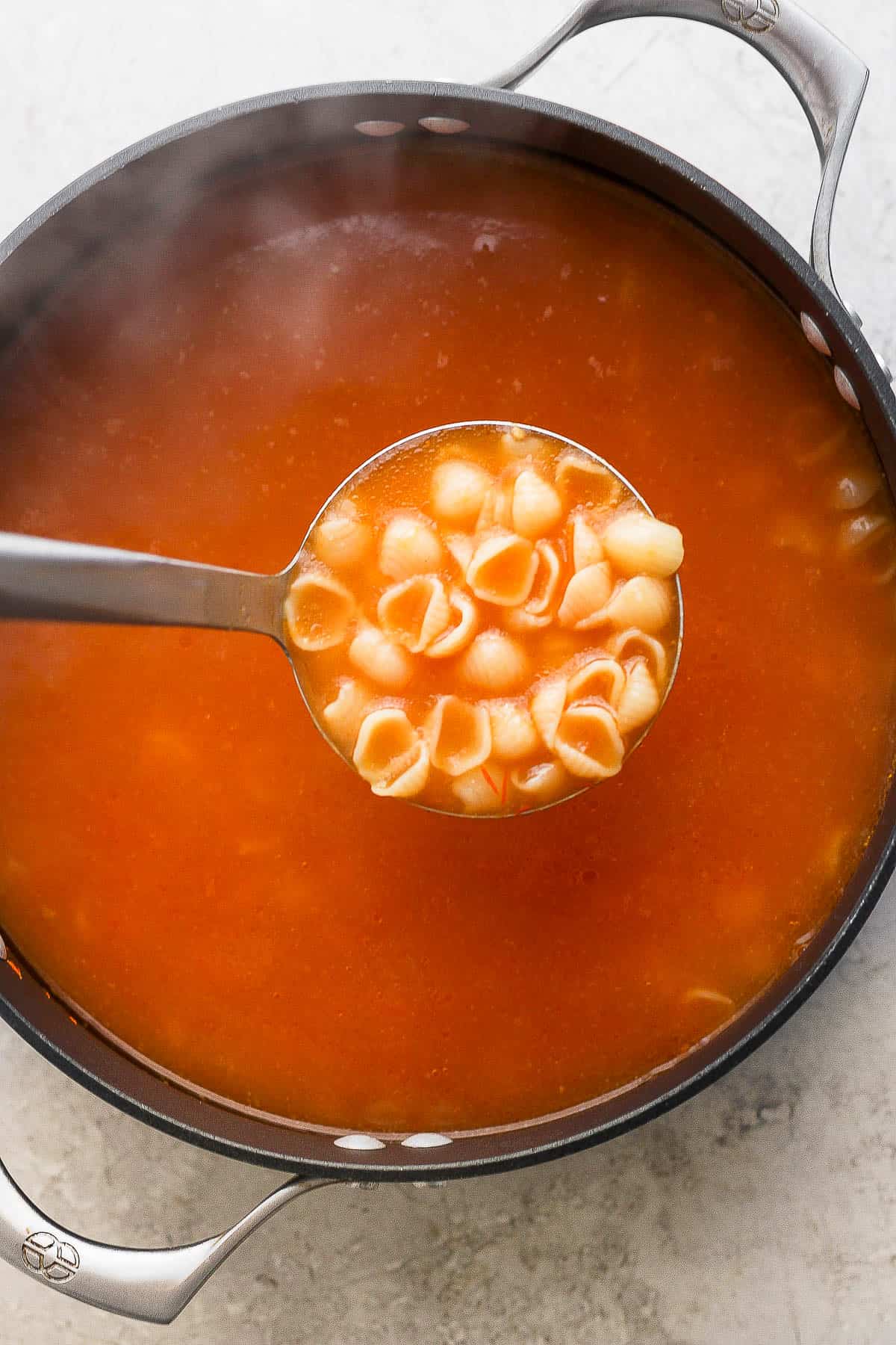 A ladle full of brothy and comforting sopa de conchas.