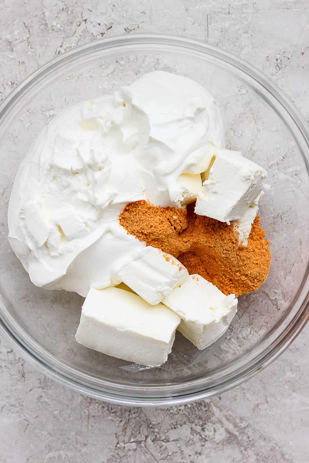 Cream cheese, sour cream, and taco seasoning in a bowl.