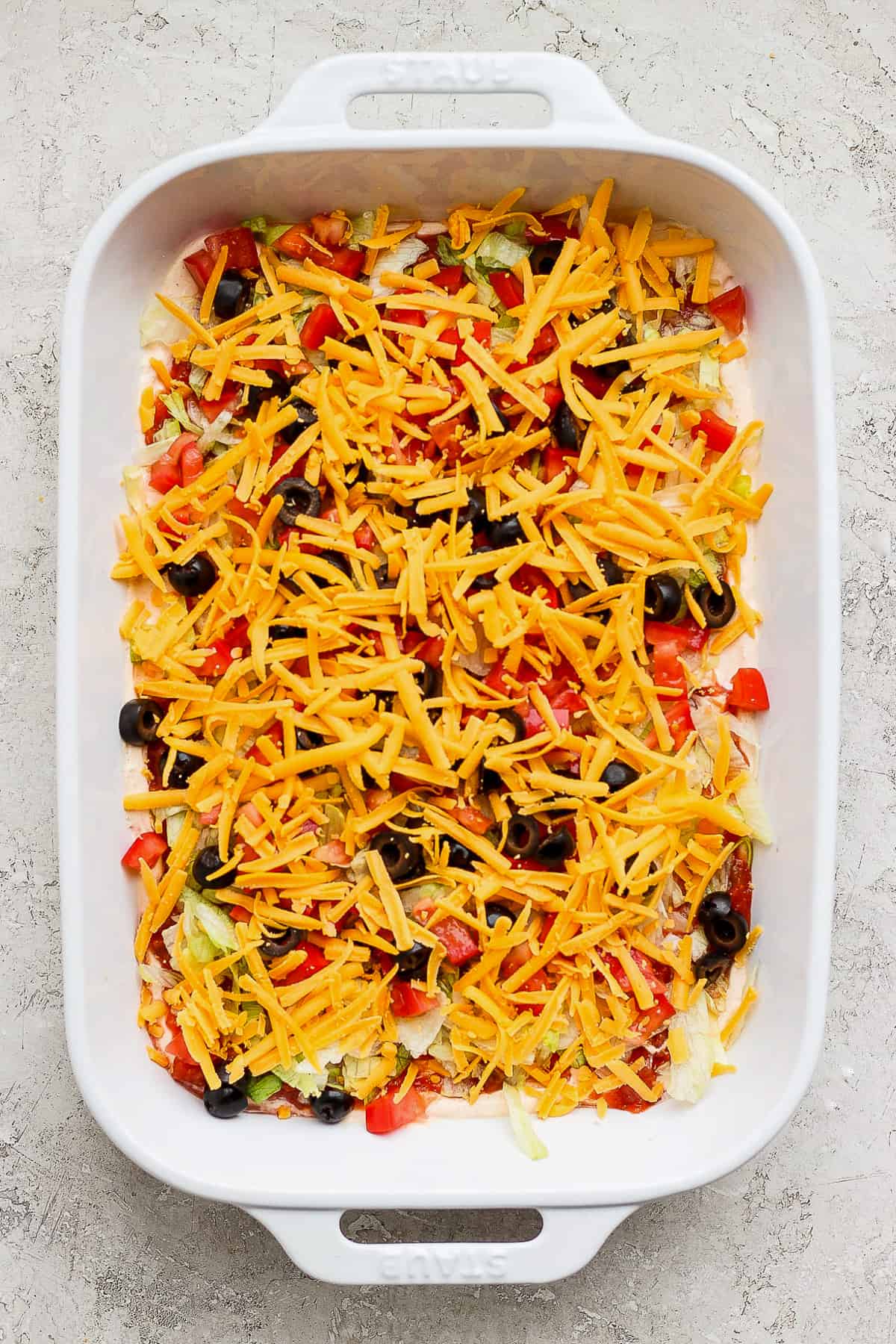 A taco dip in a casserole baking dish ready to be served.