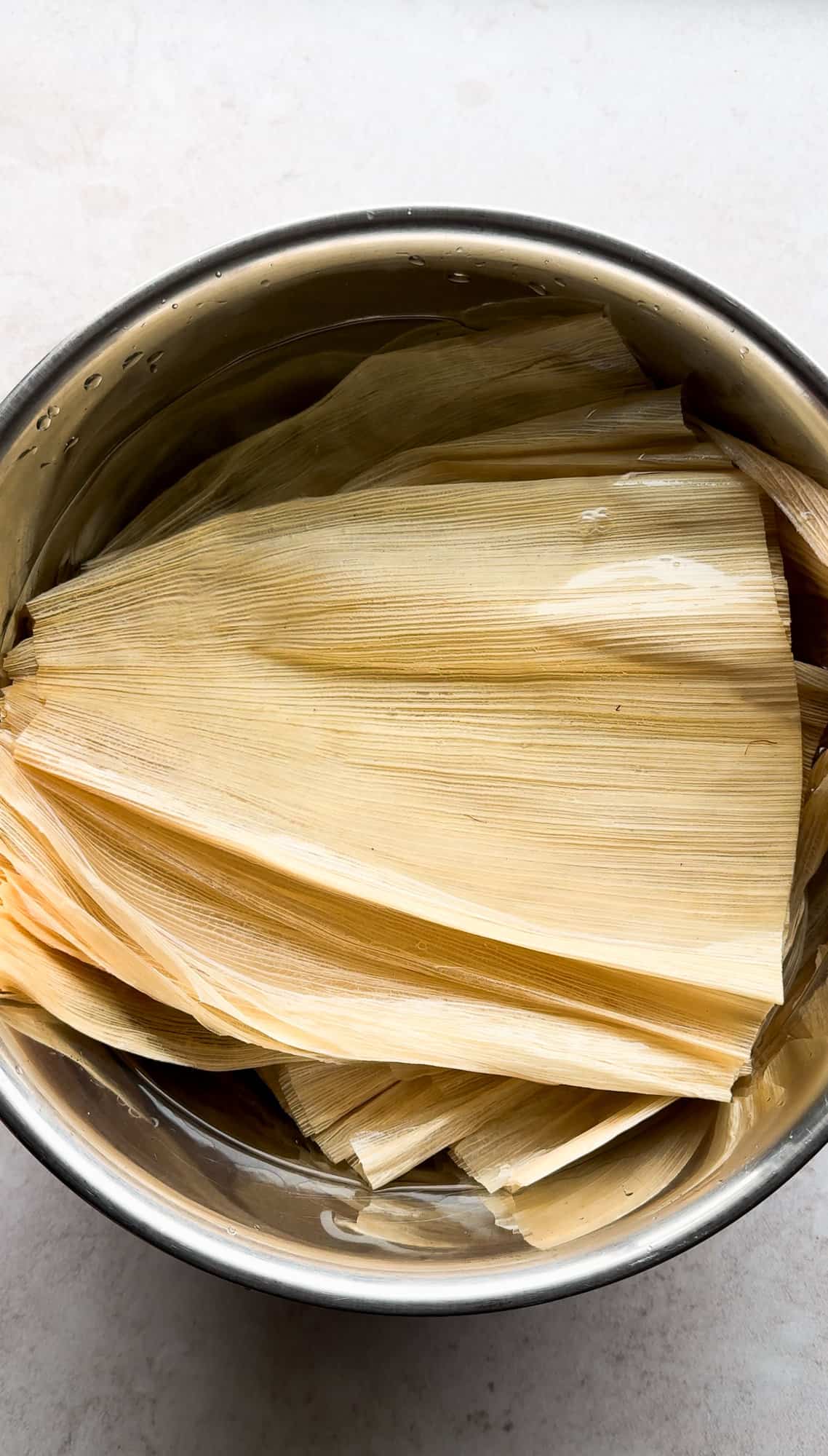 Corn husks in a bowl of water being softened for tamales.