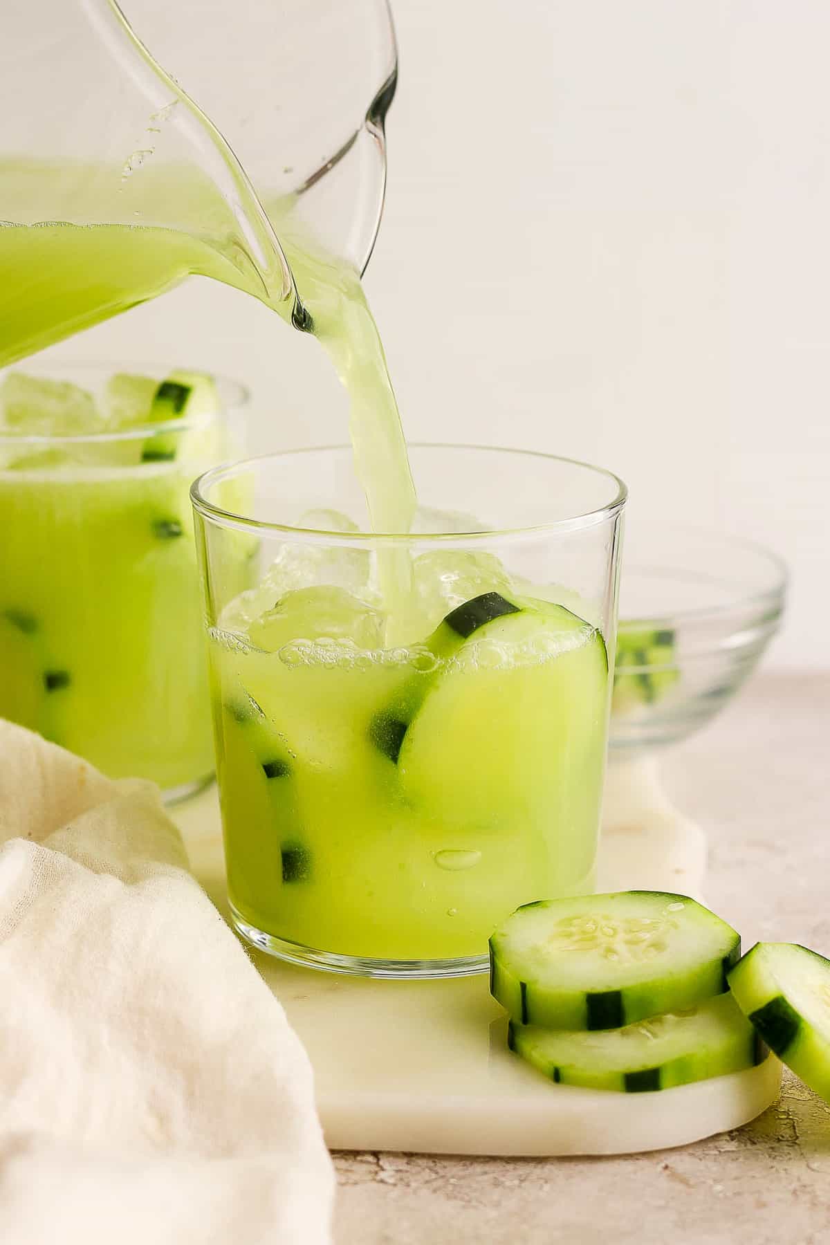 Agua de pepino being poured into an glass of ice.
