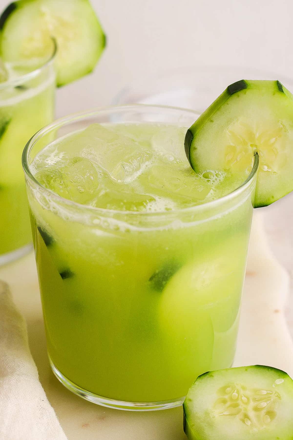 A glass of iced agua de pepino (mexican cucumber agua fresca) garnished with fresh cucumber slices.