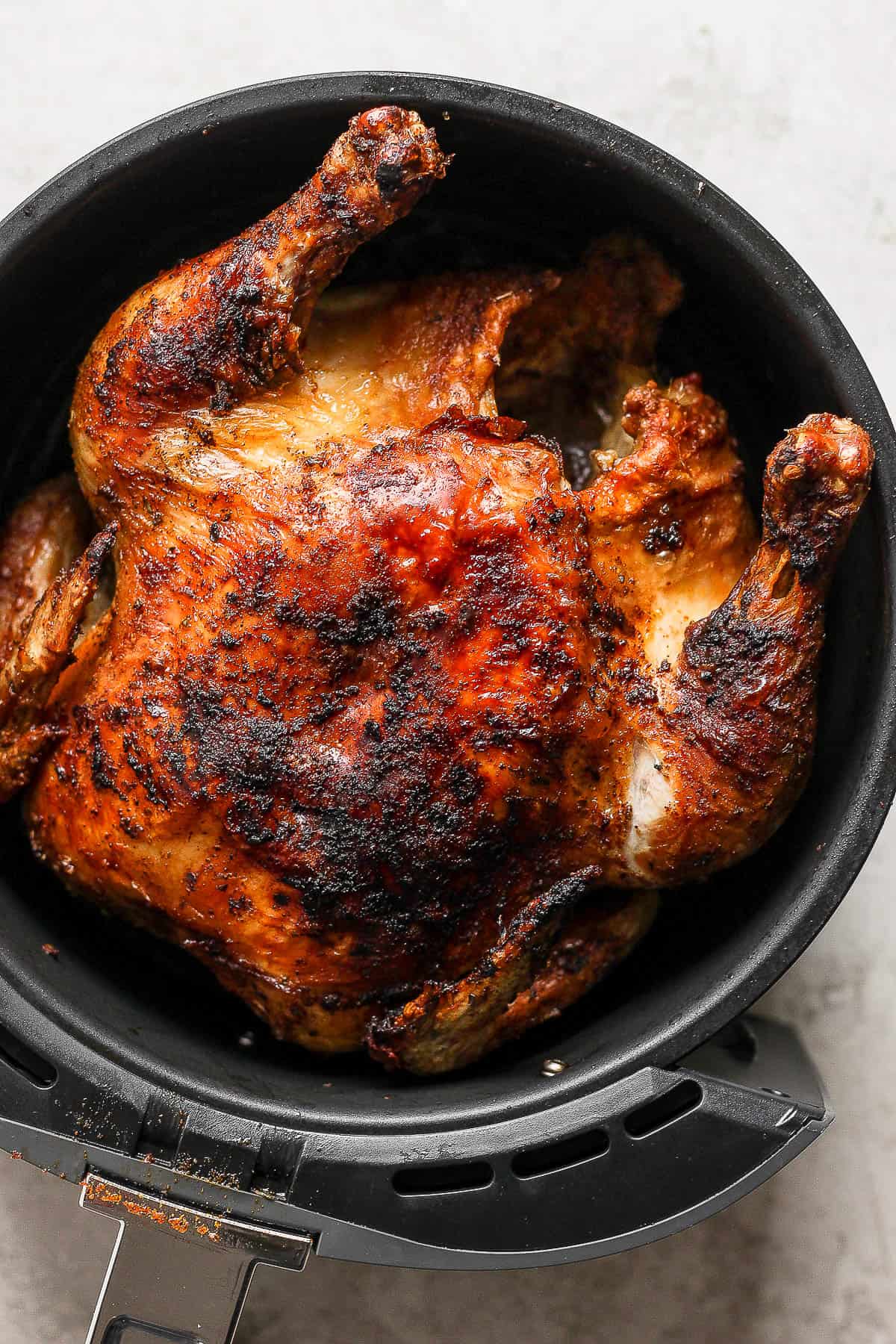 A crispy and golden air fryer whole chicken resting on a table.