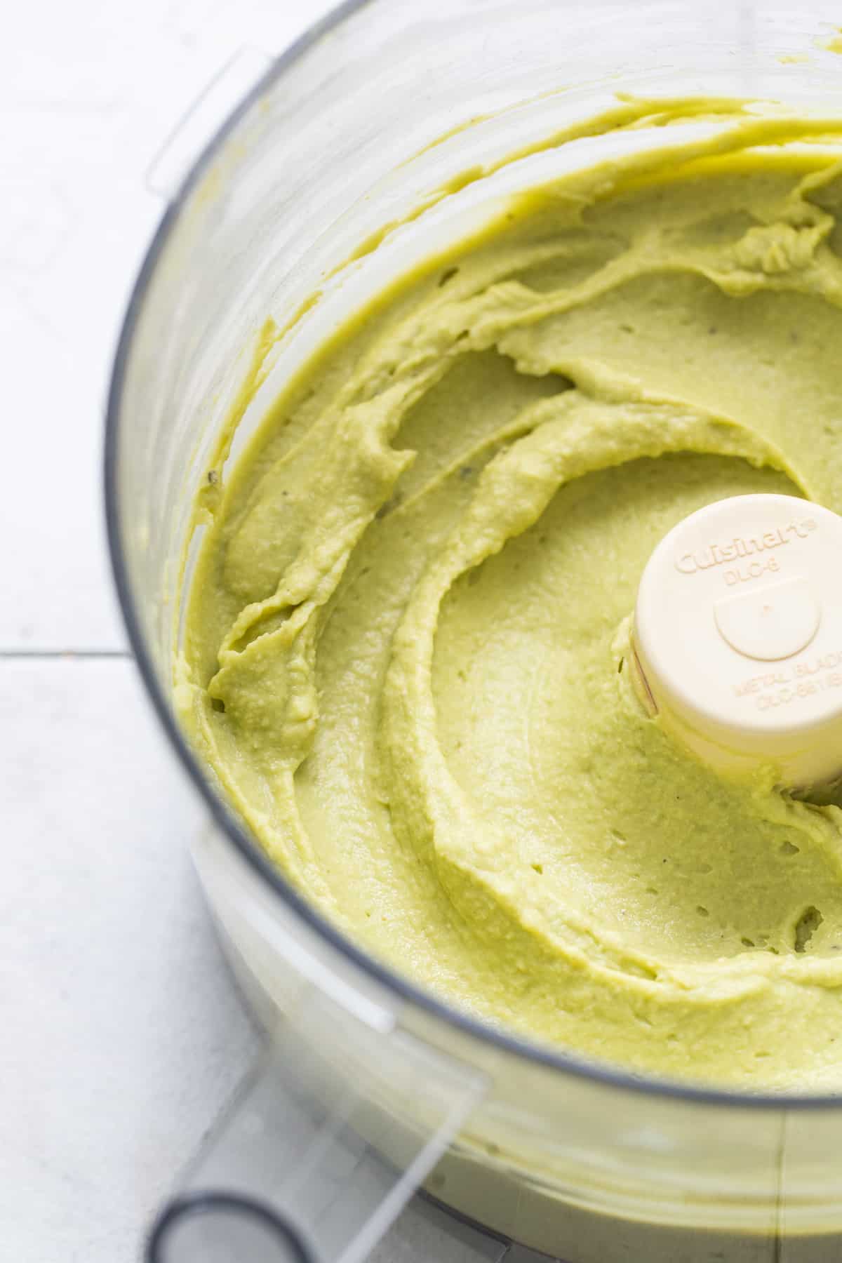 Smooth and creamy avocado hummus in a food processor.