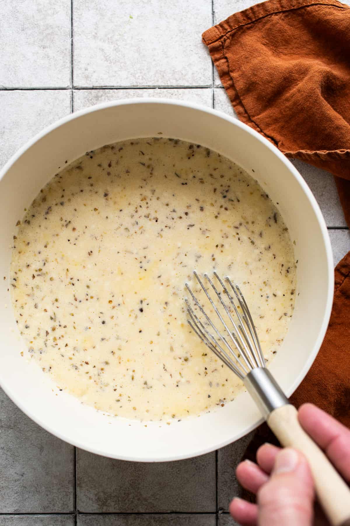 The egg mixture for chile relleno casserole in a large bowl being whisked.