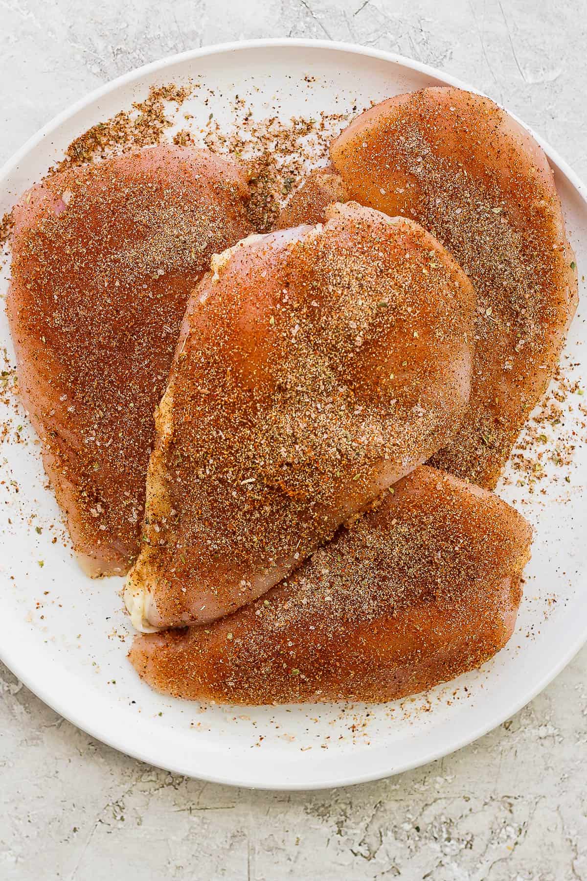 Seasoned chicken breast on a plate.