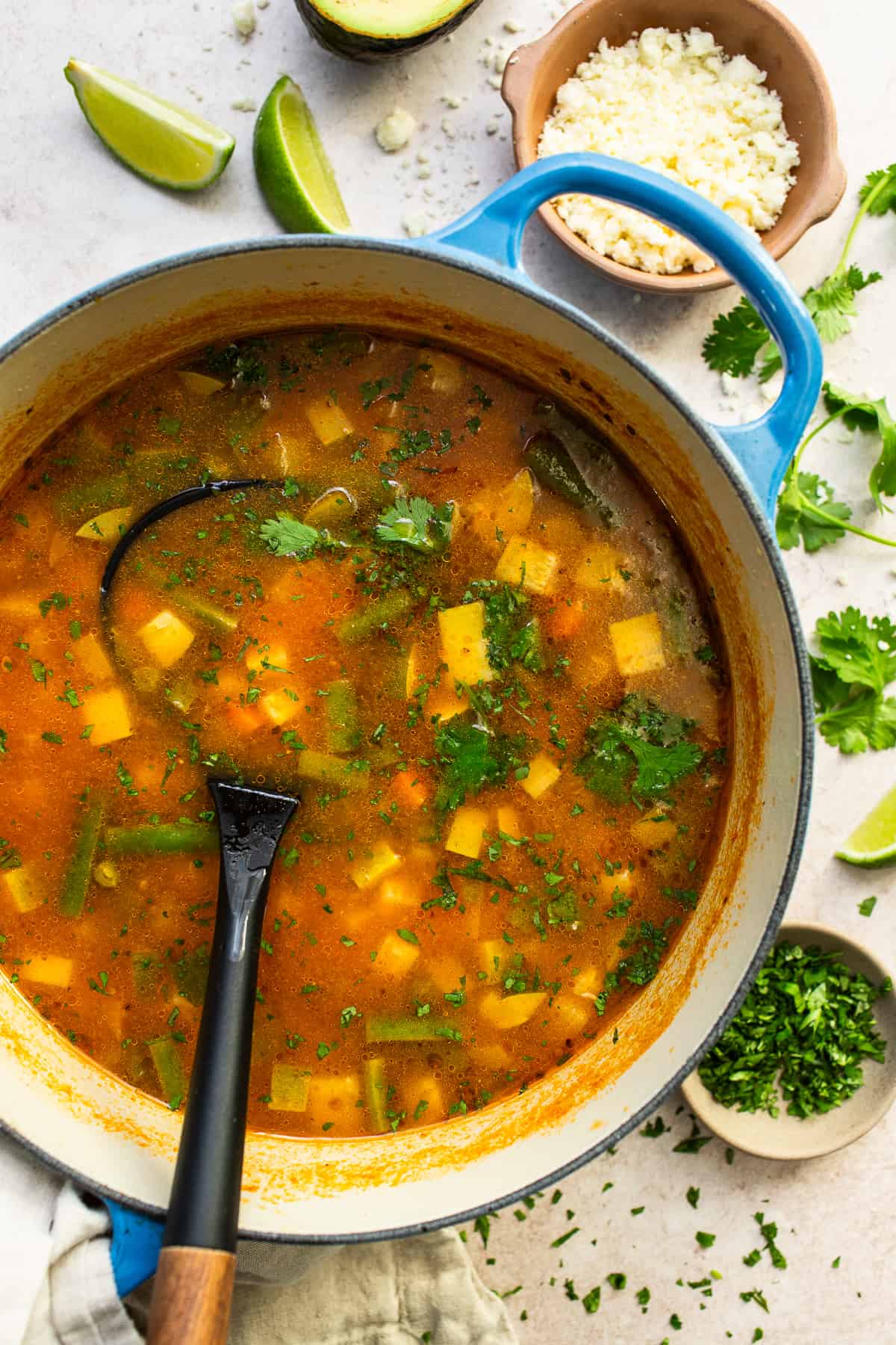 Mexican vegetable soup in a Dutch oven with a ladle getting ready to serve some of the soup.