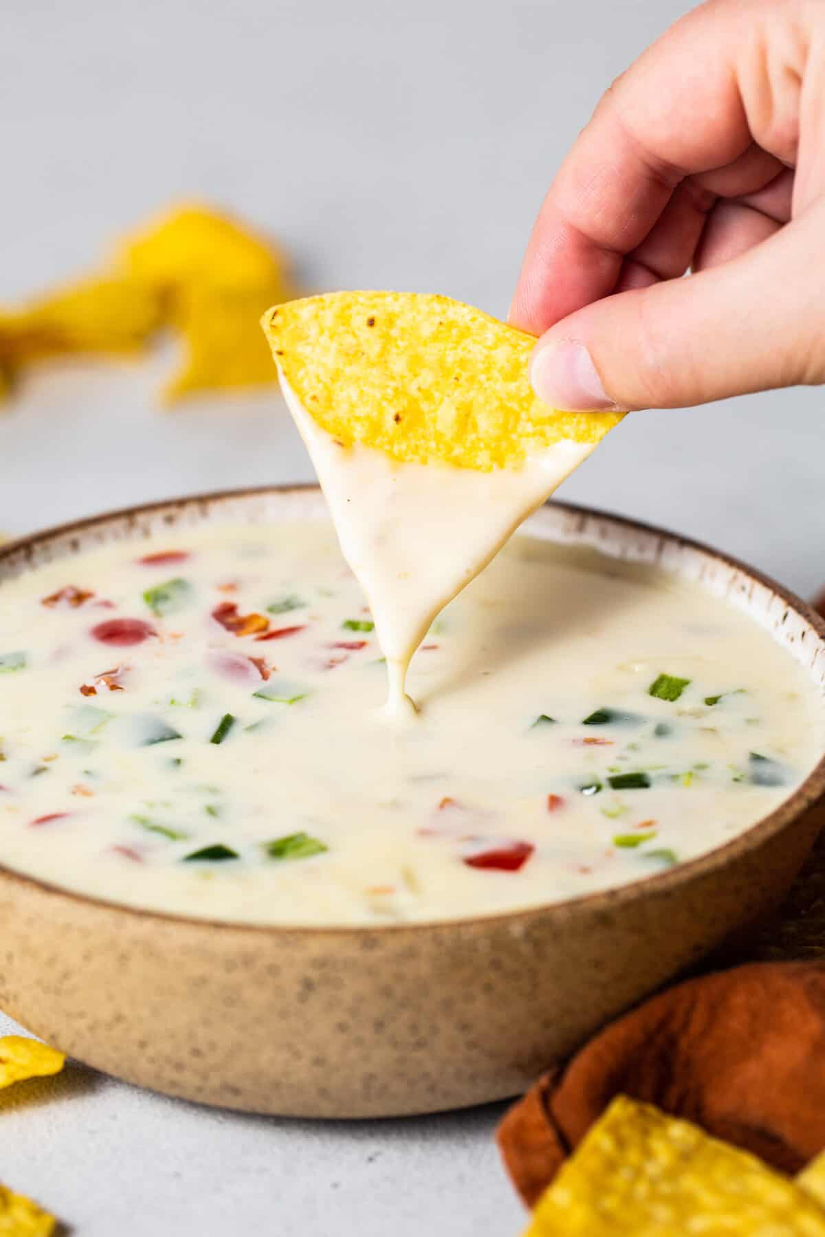A chip being dipped into a bowl of queso blanco dip.