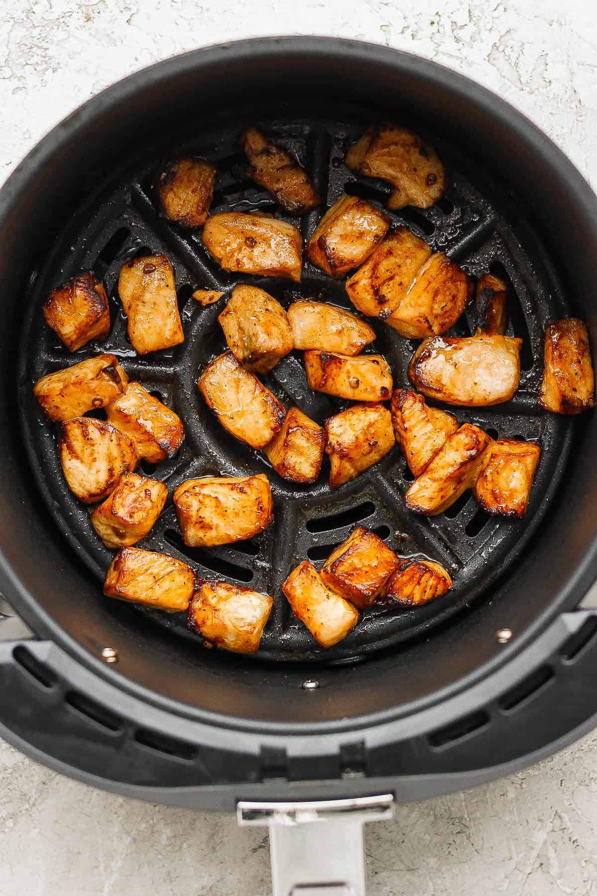 Cooked air fryer salmon bites in the basked of an air fryer before being served.