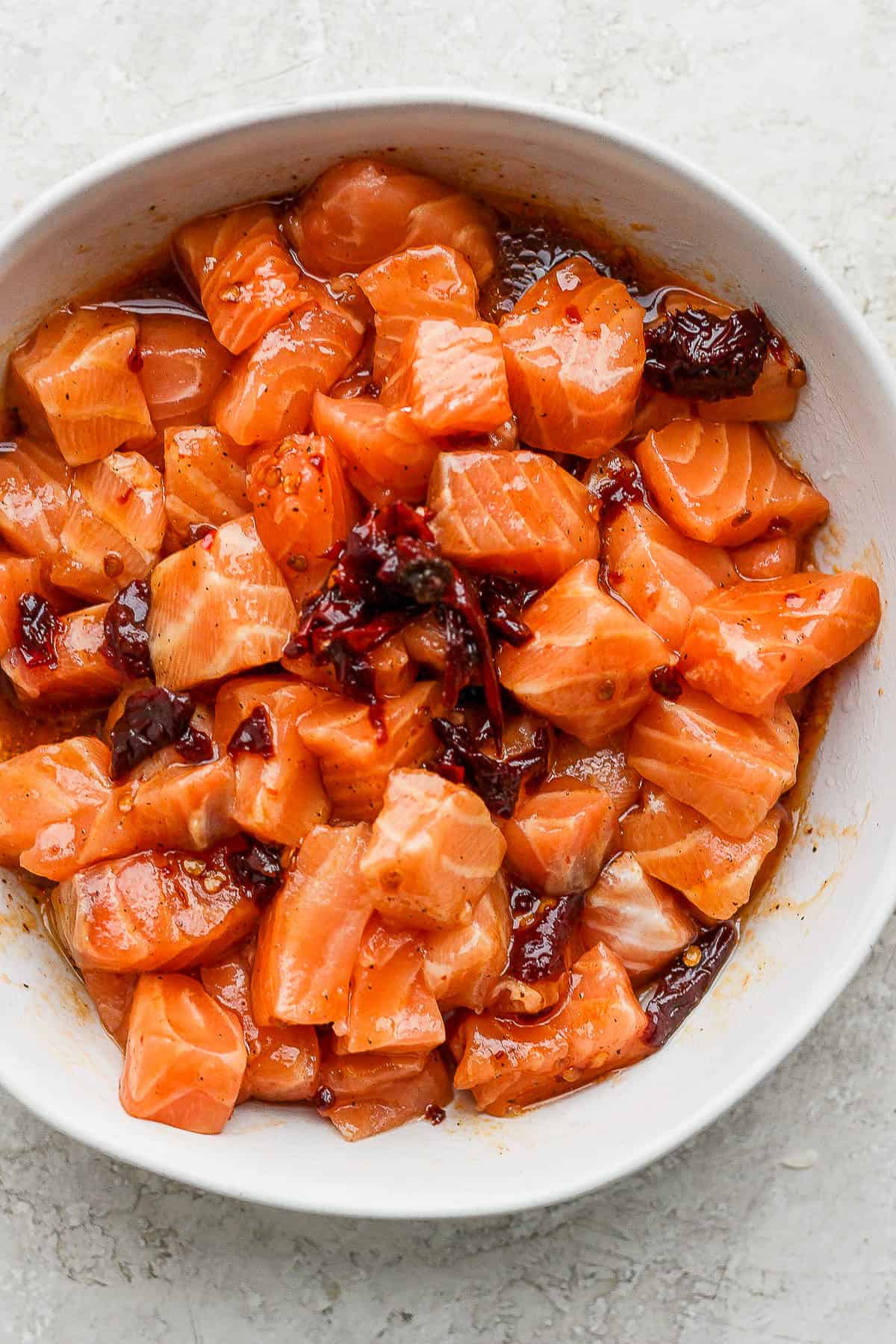 Salmon bites being marinaded in a bowl with a honey chipotle sauce.