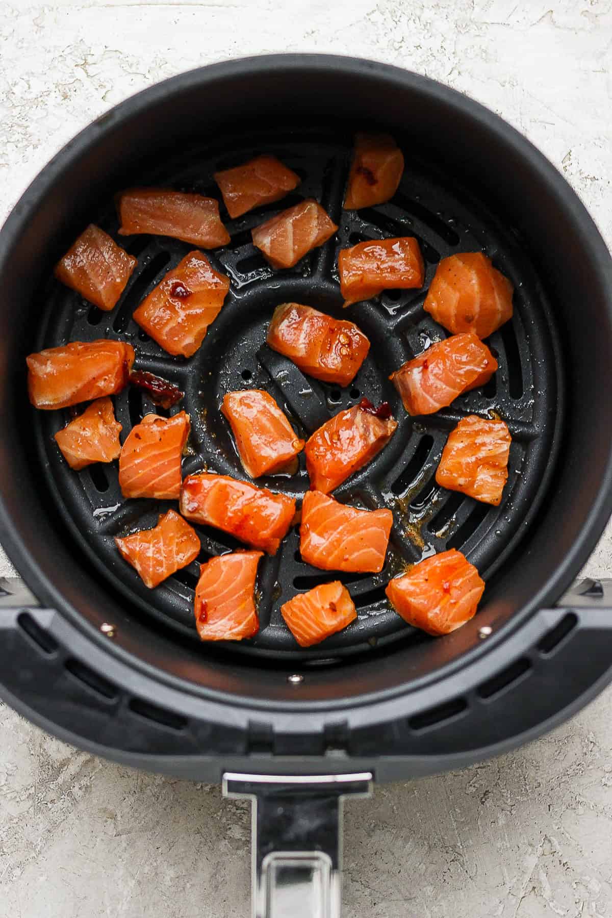 Raw salmon bites in an air fryer.