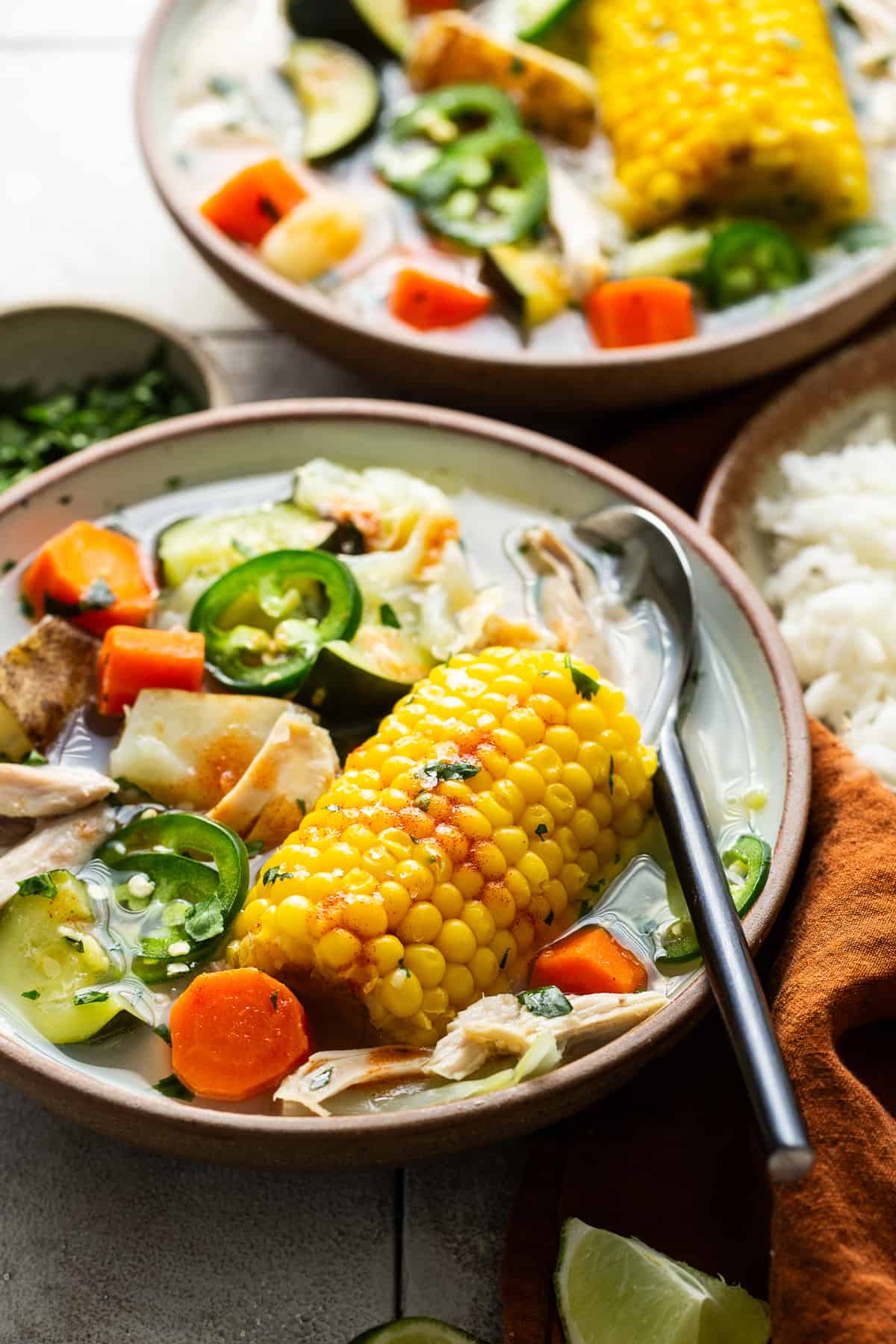 An ear of corn in a bowl of caldo de pollo.