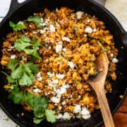 Chorizo and eggs in a skillet garnished with queso fresco and cilantro.