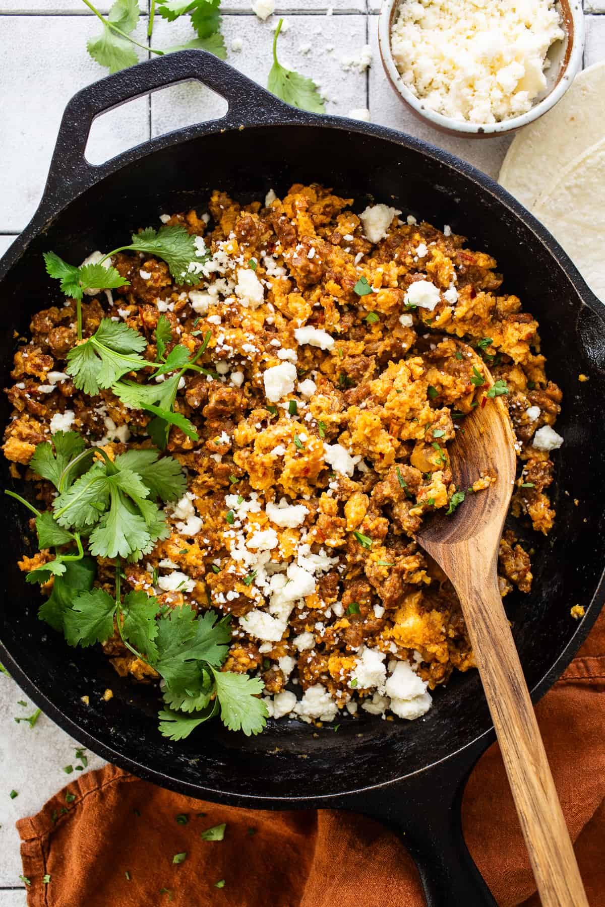 Chorizo and eggs in a skillet garnished with queso fresco and cilantro.