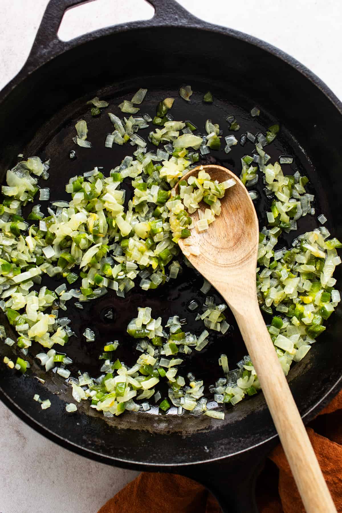 Diced onion and jalapeño being cooked in a skillet with butter.