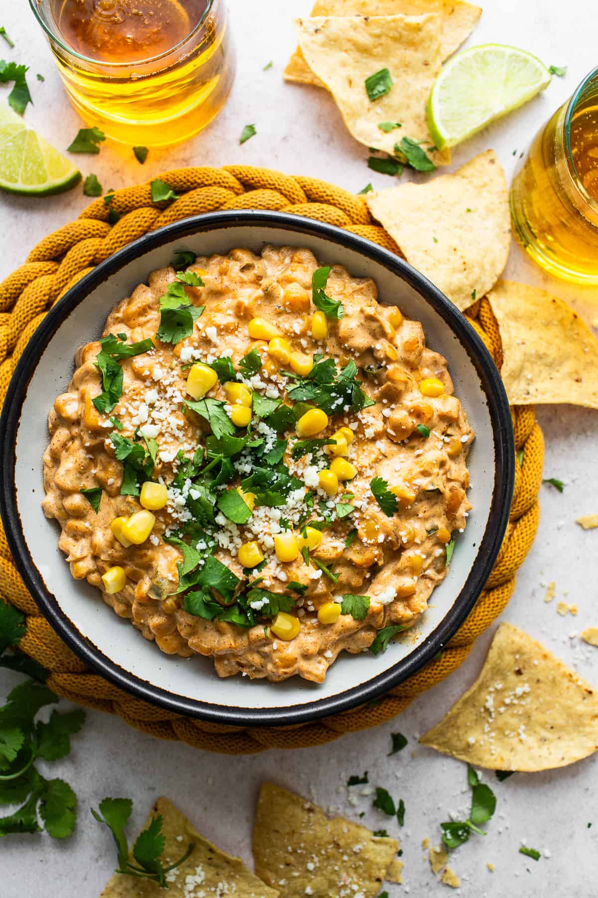 A bowl of Mexican corn dip garnished with cilantro and cotija cheese.