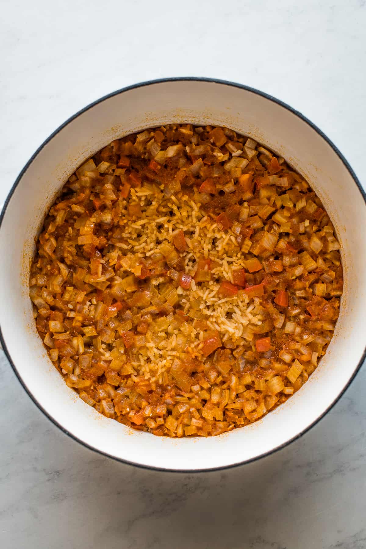 Cooked arroz rojo (mexican rice) in a pot before being fluffed with a fork.