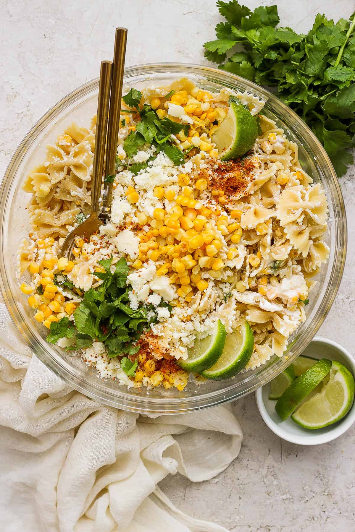 Mexican street corn pasta salad in a large bowl garnished with cilantro, cotija cheese, and tajin.