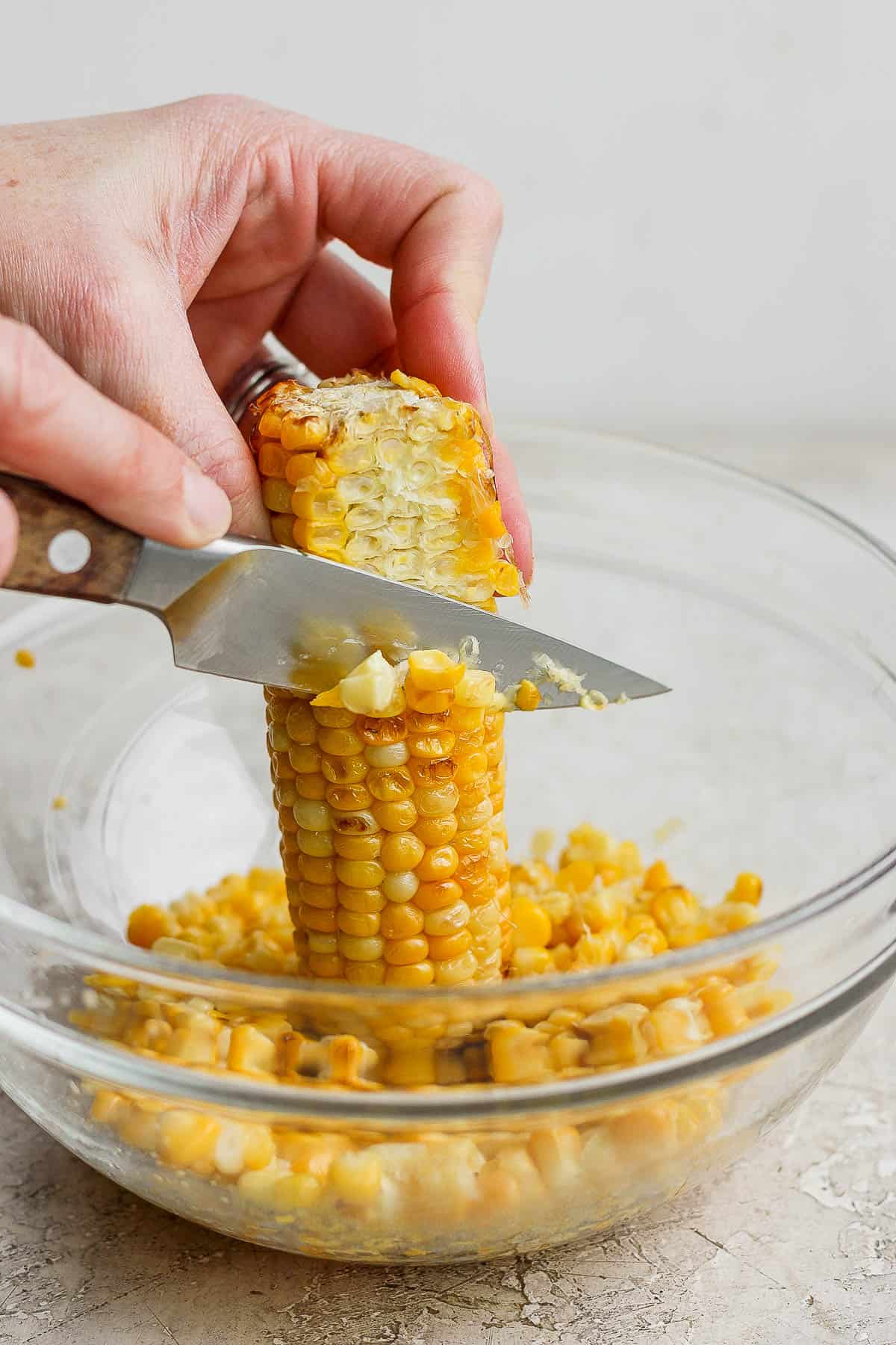 Cooked corn being sliced off the cob.