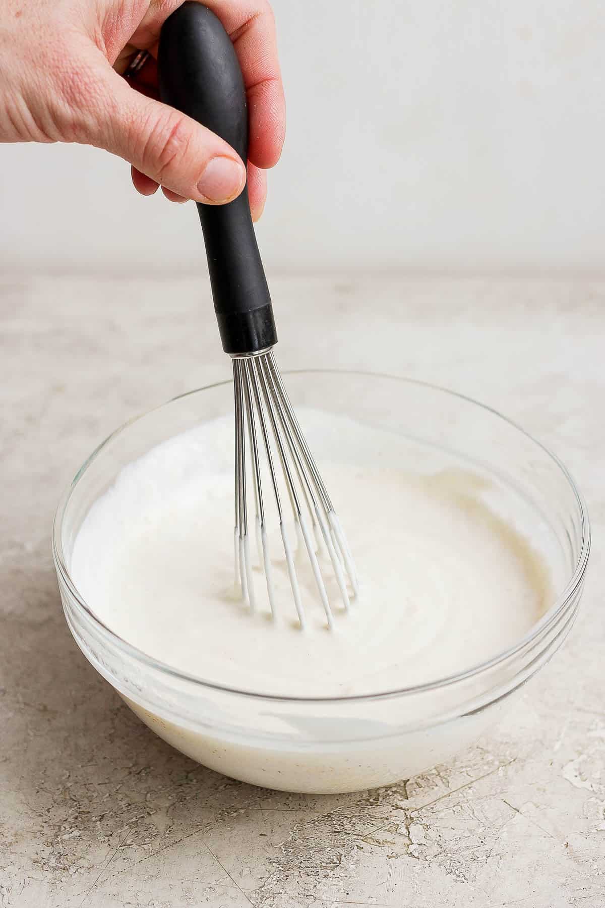 Mayonnaise sauce being whisked in a bowl.