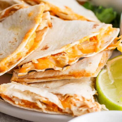 Cheesy air fryer chicken quesadillas sliced into triangles and served on a plate.